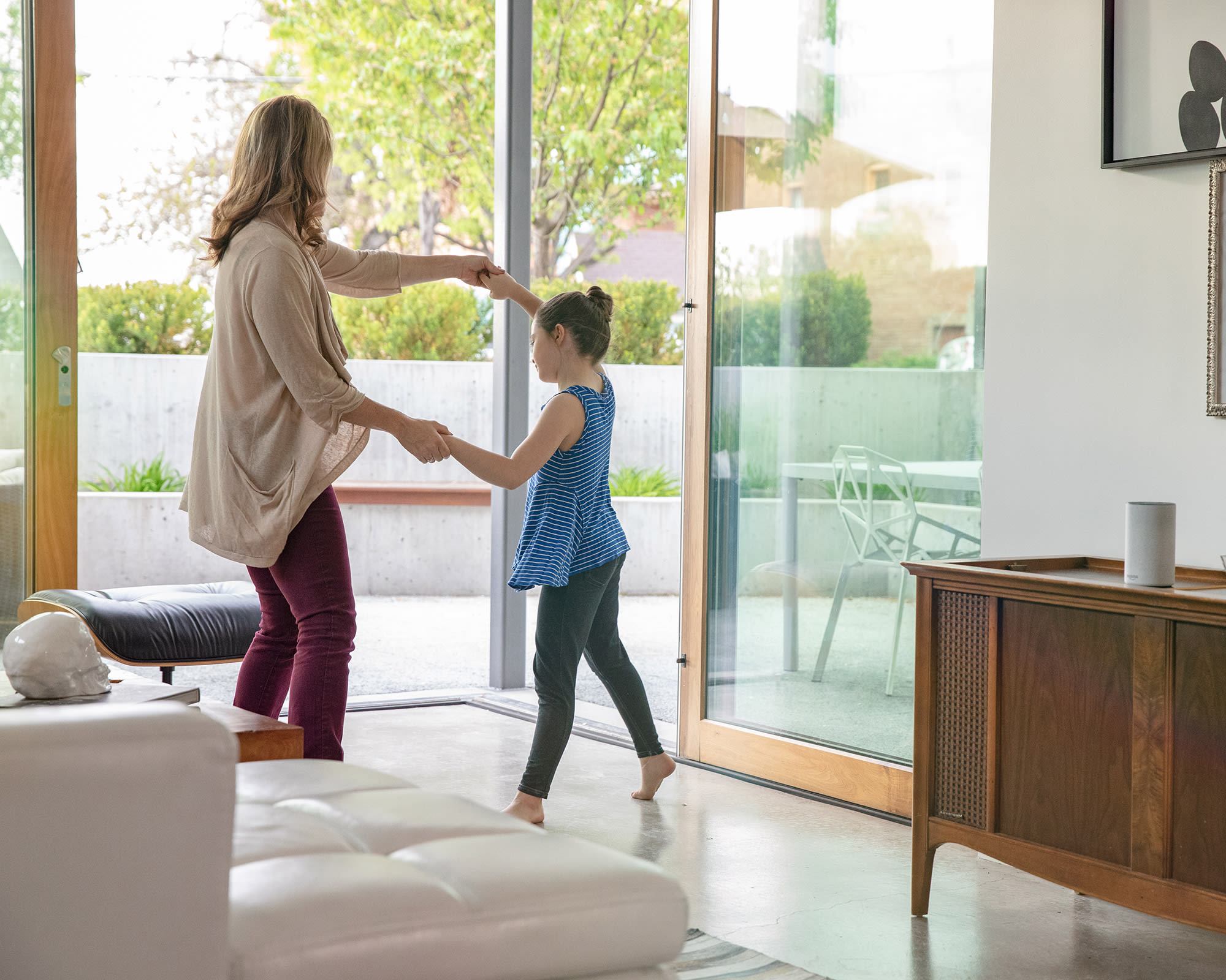 Mother and daughter dancing to connected whole-home distributed audio speakers